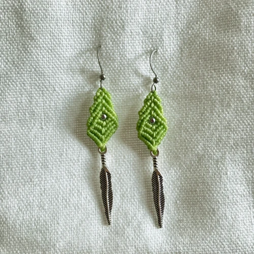 Boucles d'oreille losange en micro-macramé vert citron avec perle en acier inoxydable et plume en métal, fond tissé blanc