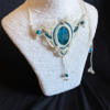 Zoom collier en micro-macramé blanc et émeraude, cabochon en apatite, perles en apatite et acier inoxydable, motifs feuilles, vue 3/4 sur présentoir neutre