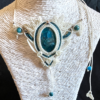 Zoom collier en micro-macramé blanc et émeraude, cabochon en apatite, perles en apatite et acier inoxydable, motifs feuilles, sur présentoir neutre