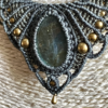 Zoom central sur un collier en micro-macramé anthracite et khaki, cabochon en labradorite, perles et breloque goutte en laiton
