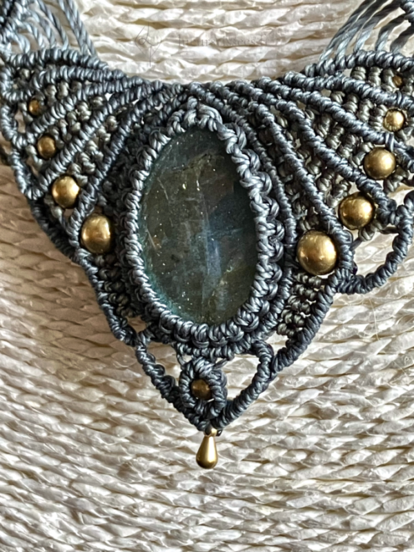 Zoom central sur un collier en micro-macramé anthracite et khaki, cabochon en labradorite, perles et breloque goutte en laiton