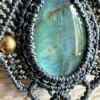 Zoom sur le cabochon en labradorite d'un collier en micro-macramé anthracite et khaki, perles en laiton