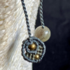 Zoom sur la finition des pendants d'un collier en micro-macramé anthracite et khaki, perles en laiton et labradorite