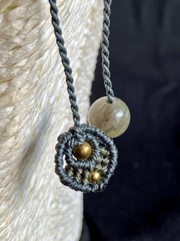 Zoom sur la finition des pendants d'un collier en micro-macramé anthracite et khaki, perles en laiton et labradorite