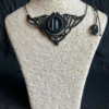 Collier en micro-macramé noir et gris avec cabochon en verre noir et blanc, sur un présentoir