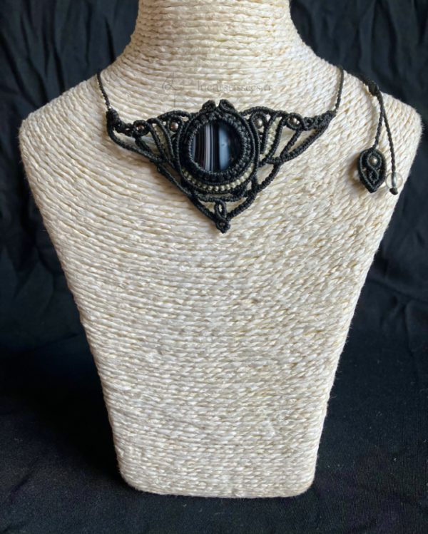 Collier en micro-macramé noir et gris avec cabochon en verre noir et blanc, sur un présentoir