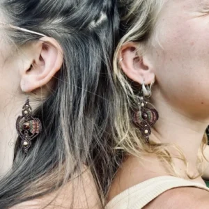 Zoom sur une paire de boucles d'oreilles en micro-macramé marron acajou, cannelle et vert olive, graine d'açaï marbrée, perles en laiton, motif rayonnant, portée par deux personnes dos à dos