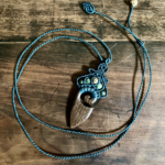 Pendentif en micro-macramé émeraude, élément en bois massif : wengé, perles en jaspe paysage et turquoise d'Afrique, posé sur une table en bois