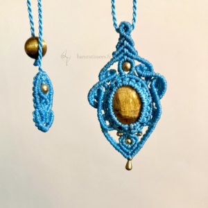 Zoom pendentif en micro-macramé bleu turquoise, cabochon et perle œil de tigre, perles et breloque goutte en laiton, motifs baroque, arrière plan neutre