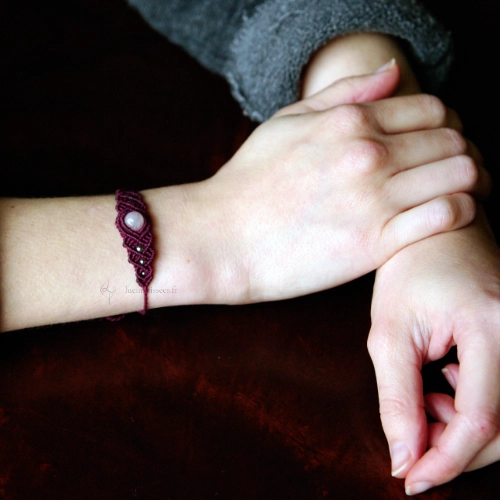 Bracelet en micro-macramé violet prune, perles en quartz rose et acier inoxydable, motif entrelacs, vue porté, zoom sur les mains