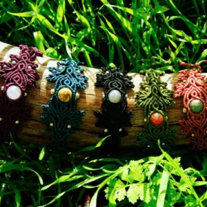 5 Bracelets en micro-macramé différentes couleurs, motifs feuilles et entrelacs, sur un support en bois, arrière plan végétation
