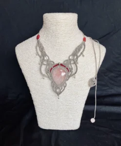 Collier en micro-macramé gris et bourgogne, cabochon quartz rose, perles cristal de roche, finitions acier inoxydable, sur présentoir neutre, fond noir