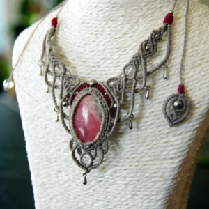 Collier en micro-macramé gris et bourgogne, cabochon rhodonite, perles en cristal de roche, finitions en acier inoxydable, vue 3/4 sur présentoir neutre