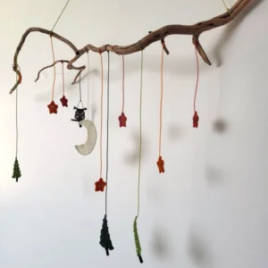 Mobile suspendu contre un mur blanc, sapins, étoiles, Lune et hiboux en micro-macramé, support branche tortueuse