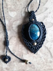 Pendentif en micro-macramé noir, cabochon apatite, perles en laiton, motifs baroques, médaillon, zoom posé sur un carreau de faïence