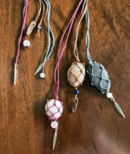 3 pendentifs galets naturels sertis en filet, sur une table en bois