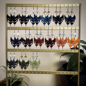 15 paires de boucles d'oreilles en micromacramé suspendues sur un support