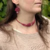 Zoom visage femme de 3/4 portant le collier ras du cou et les boucles d'oreilles Arborescence framboise et quartz rose