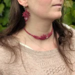Zoom visage femme de 3/4 portant le collier ras du cou et les boucles d'oreilles Arborescence framboise et quartz rose