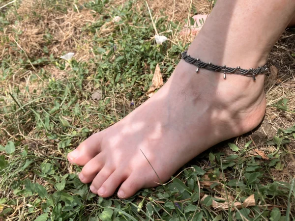Photo bracelet de cheville en micro-macramé vert khaki avec perles et breloques en forme de gouttes en acier inoxydable, porté, arrière plan herbe